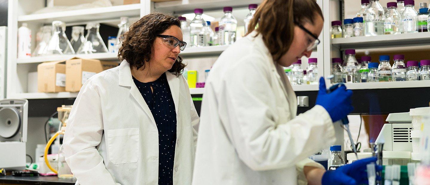 两个女人在实验室里拿着玻璃瓶里的化学药品.